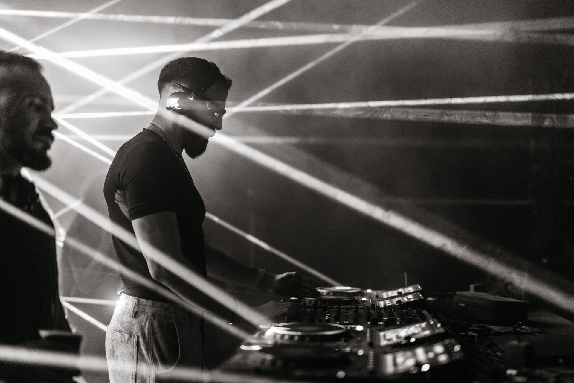 Black and white portrait of a DJ under laser lights