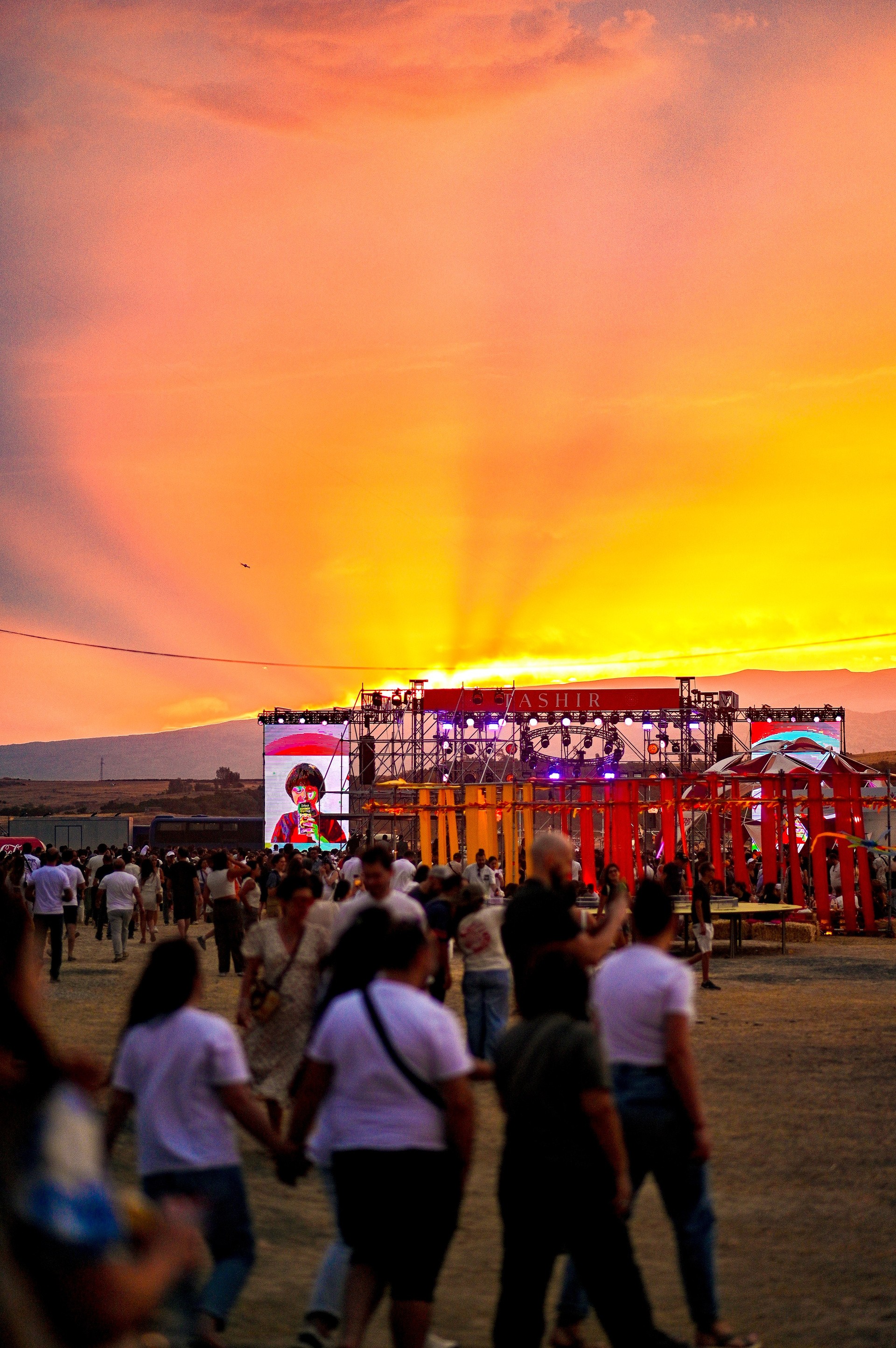 Crowd walking toward the Tashir stage at golden-hour sunset